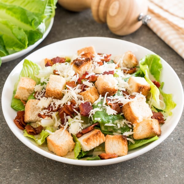 Caesar salad with crisp romaine lettuce, croutons, bacon bits, and shredded Parmesan cheese.